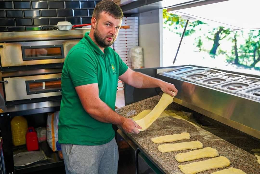 Brutar The Irish Truck în tricou verde întinzând aluat proaspăt în truck, lângă cuptoare